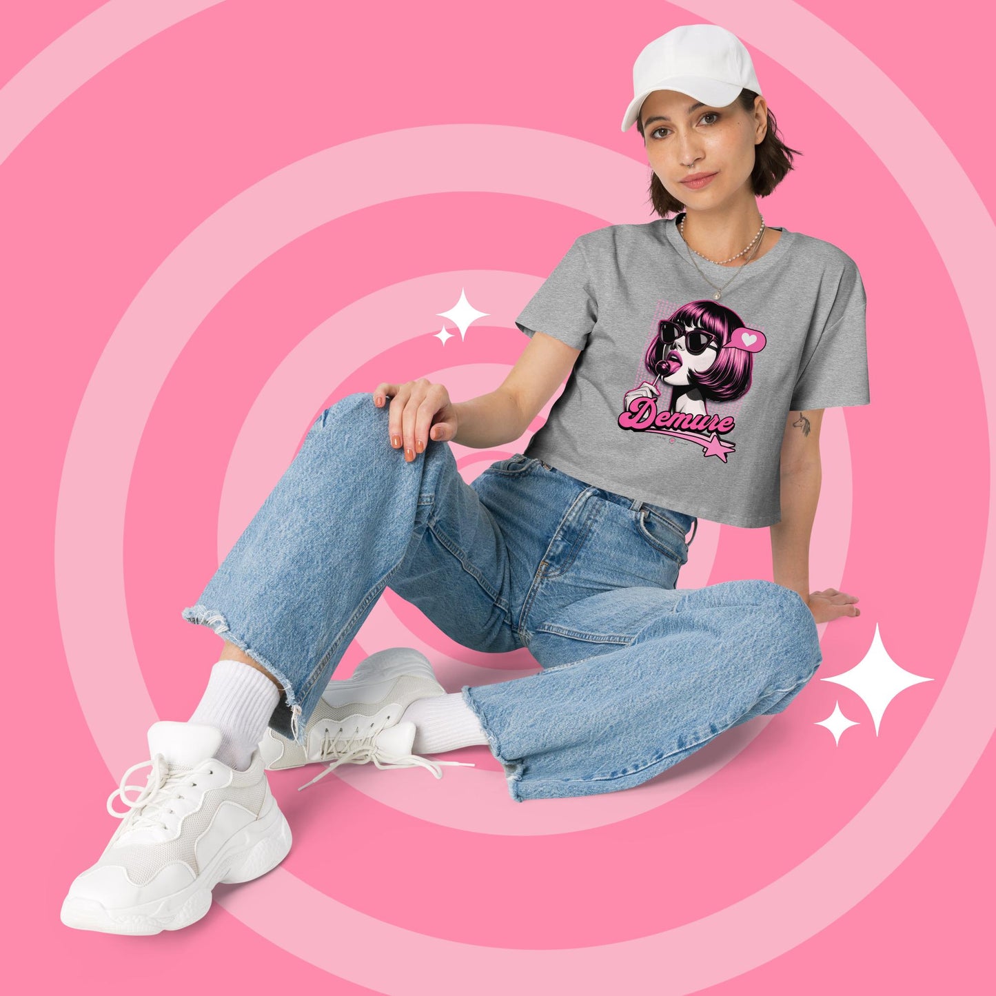 Woman wearing a heather grey cropped graphic T-shirt and jeans sitting.