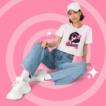 Woman wearing a pale pink cropped graphic T-shirt and jeans sitting.